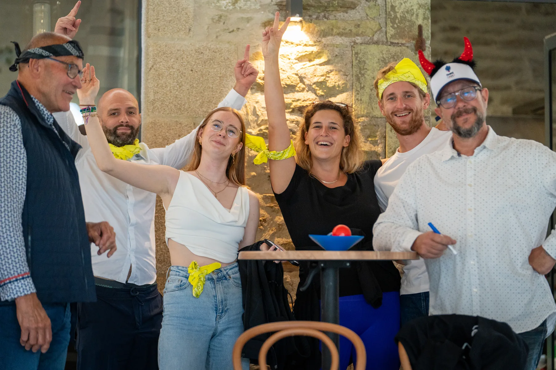 Équipe hilare aux foulards jaunes levant les bras