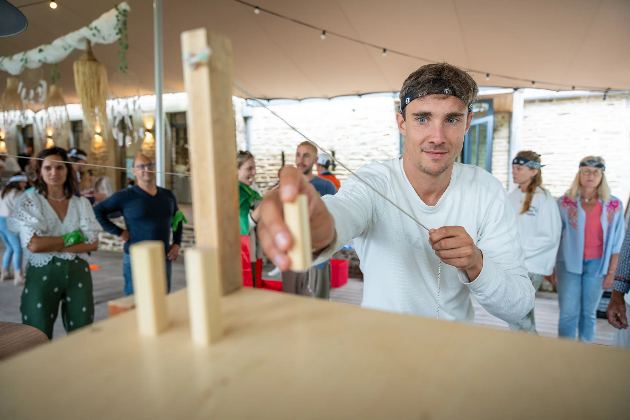 Participant concentré sur un jeu d’adresse en bois lors d’une animation de groupe