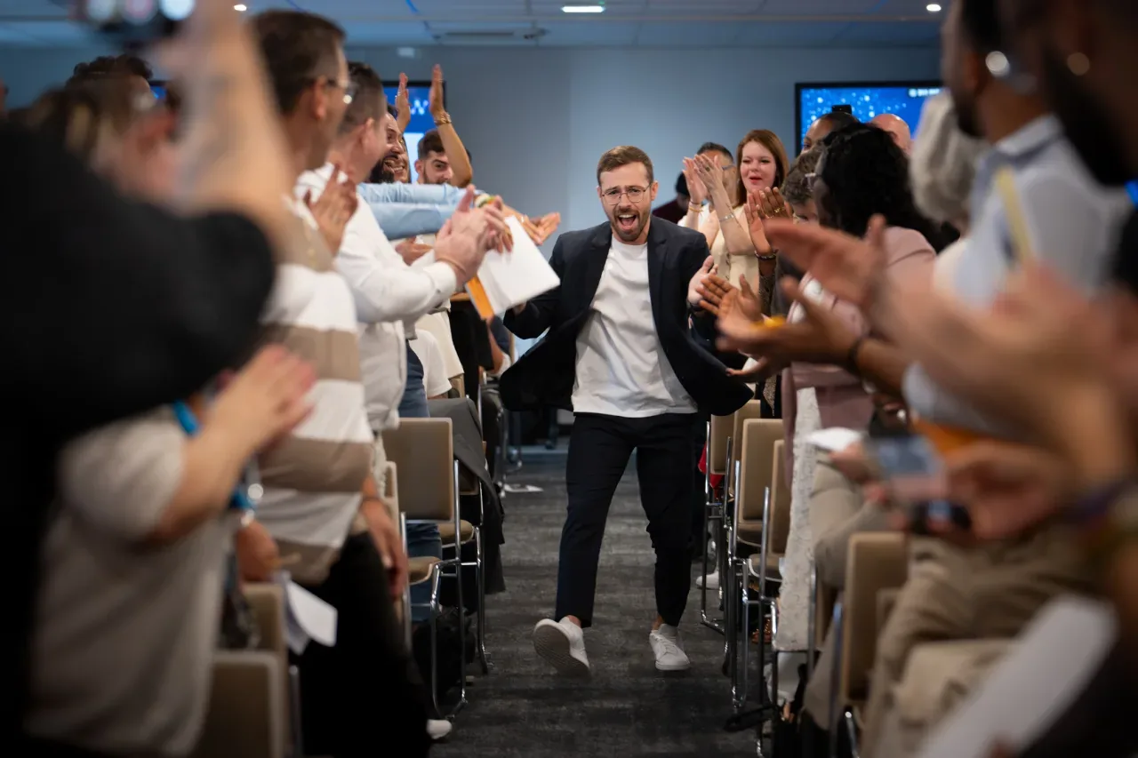 Participant acclamé traversant la salle sous les applaudissements de ses collègues