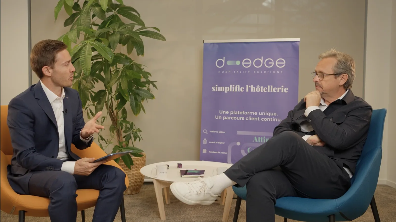 Plateau d'interview D-EDGE : un intervieweur et son invité en fauteuils, devant le kakémono D-EDGE Hospitality Solutions