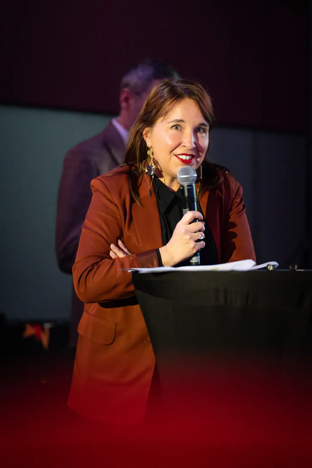 Intervenante au pupitre, micro en main, lors d'une convention d'entreprise