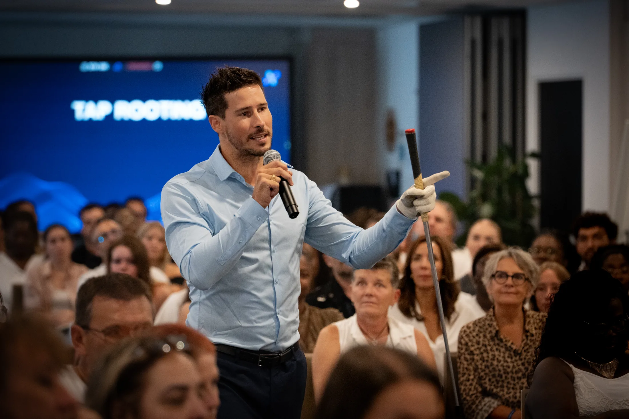 Orateur au micro face à une salle comble lors d'une convention d'entreprise à Montpellier, photographié par Robin Sforza