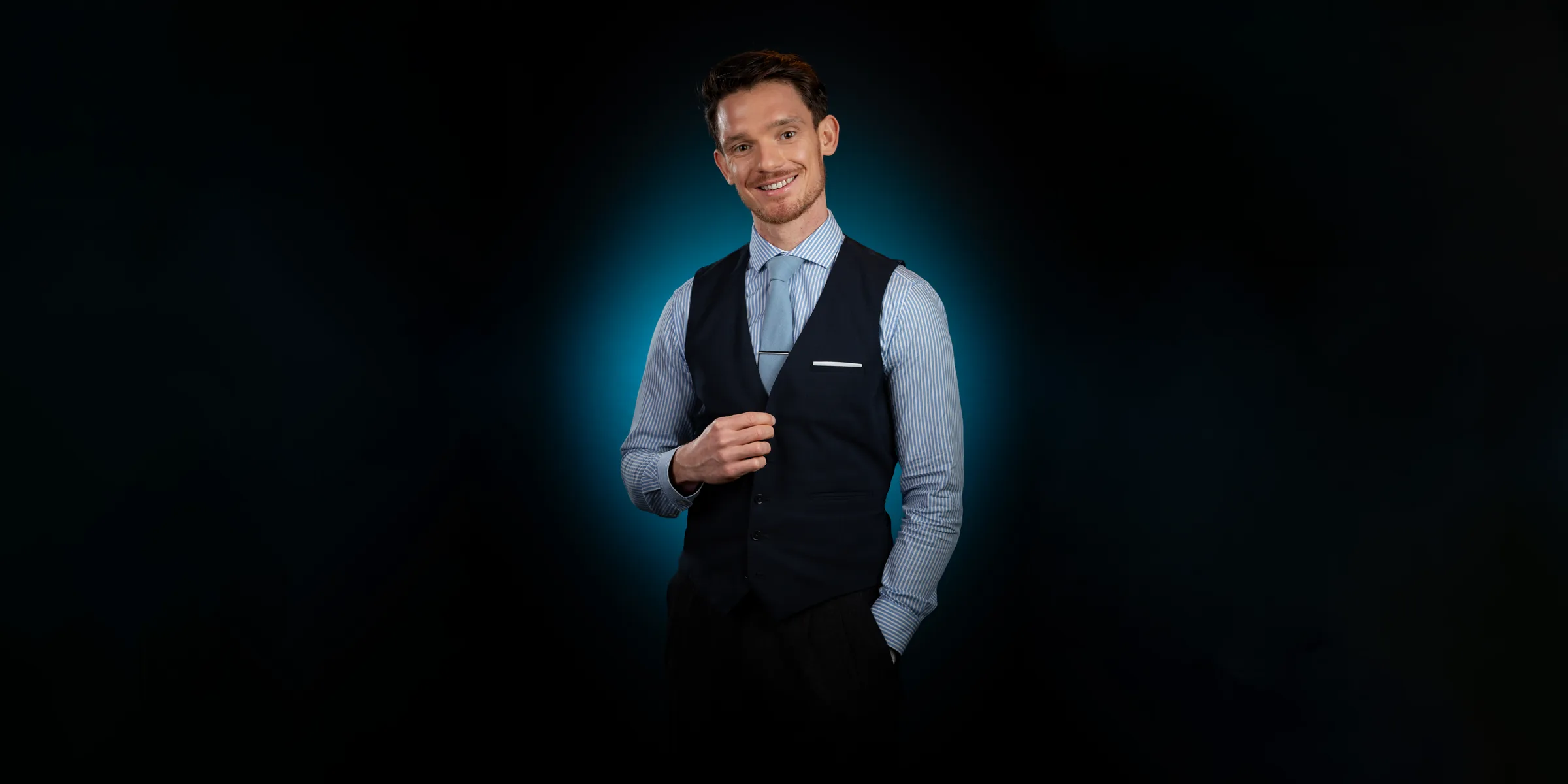 Portrait professionnel en studio d’un homme souriant en gilet et cravate