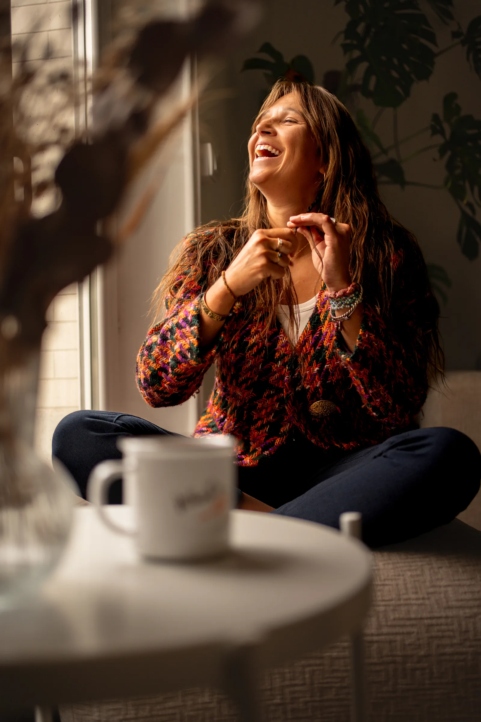 Comédienne d'improvisation éclatant de rire, tasse de café devant elle, portrait métier en intérieur