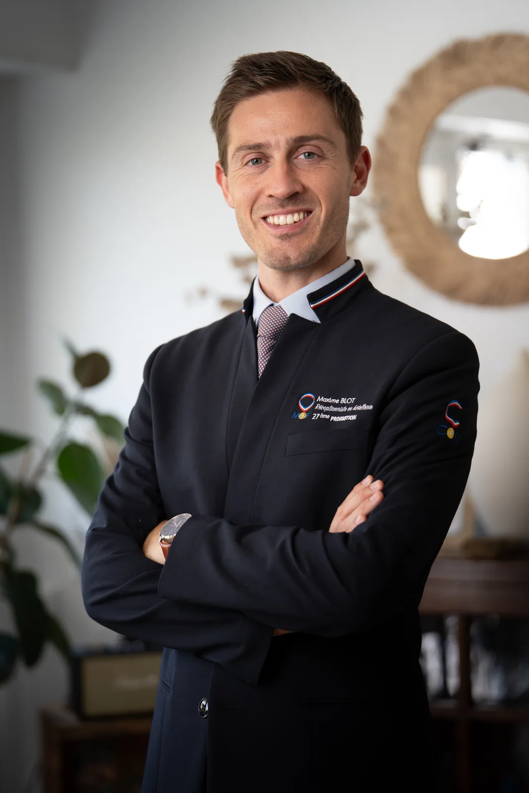 Portrait professionnel en veste et cravate, bras croisés et sourire assuré, pour Hospitality Insiders